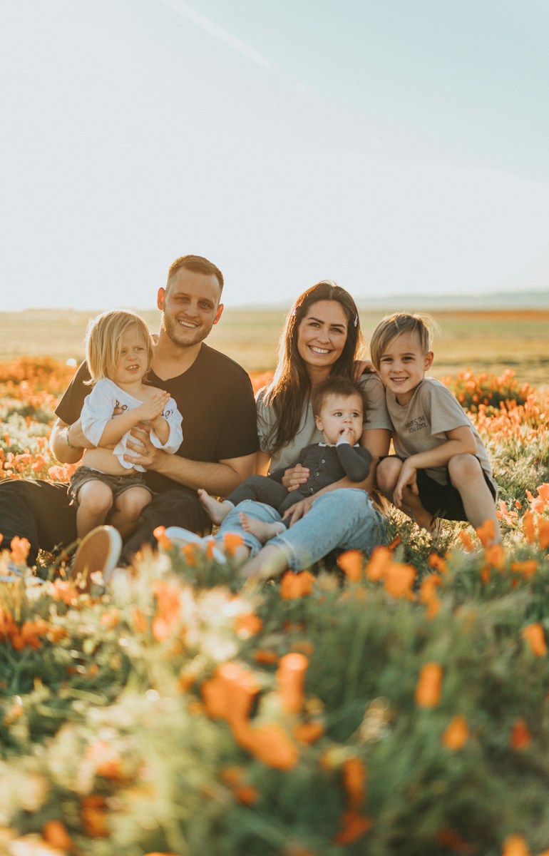 a family of 5 with life insurance sitting on a field of flowers smiling